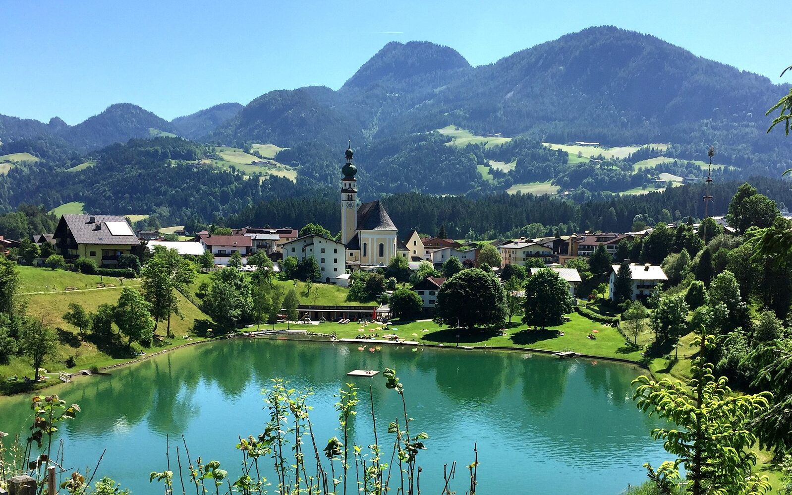 Ein von Bergen umgebener See und ein Dorf im Alpbachtal.